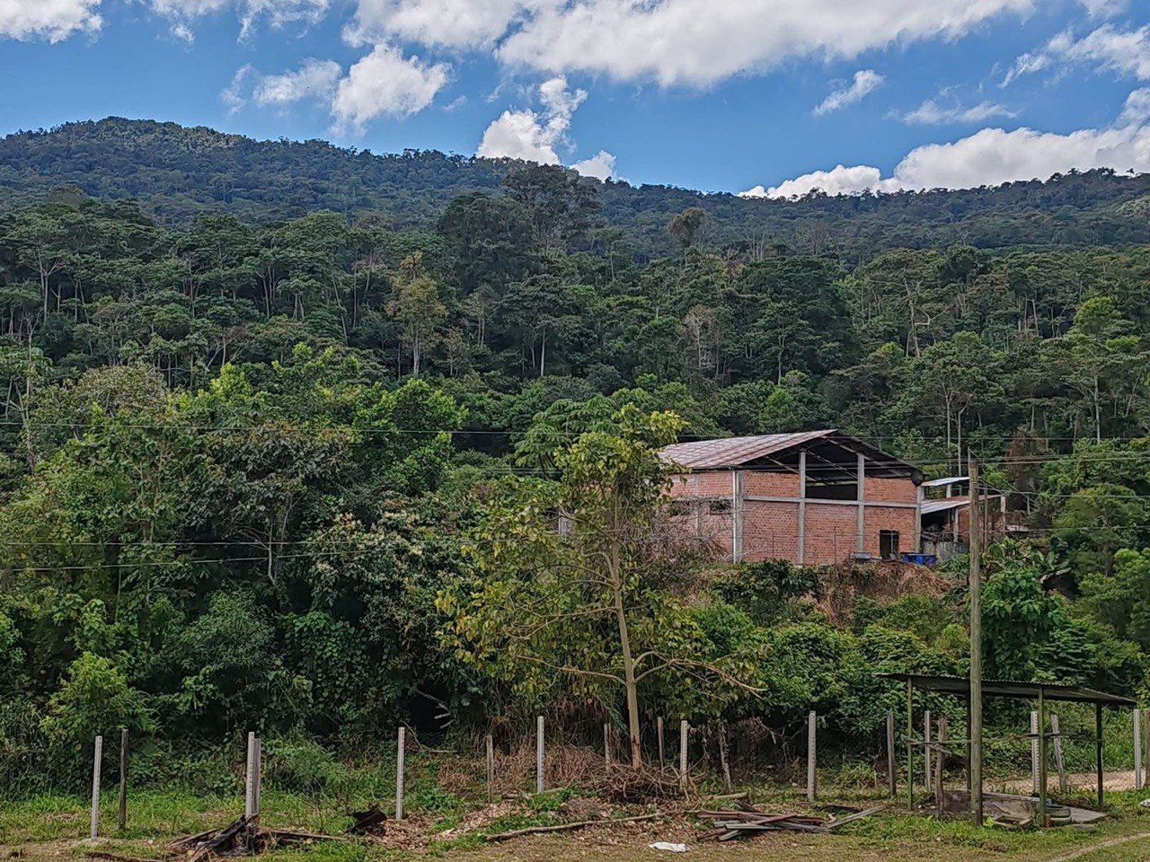 Здание станции обработки кофе среди зелёных холмов.